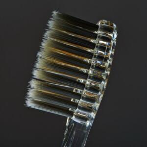 Close-up of a clear plastic toothbrush with a black and white bristle head.