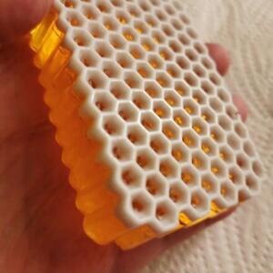 A white honeycomb-shaped soap bar with a clear, amber-coloured layer on top.