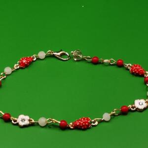 A gold chain bracelet with red and white enamel strawberry charms and white flower charms.
