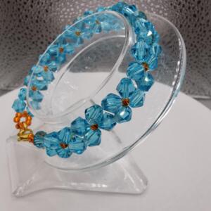 A blue crystal bracelet with gold accents. The bracelet is made of faceted beads and is strung on a clear elastic cord.