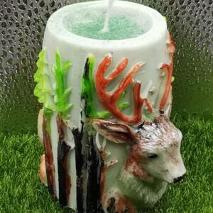 Side view of the handcrafted deer aromatic candle with raised deer head, trees, and forest-inspired decoration.